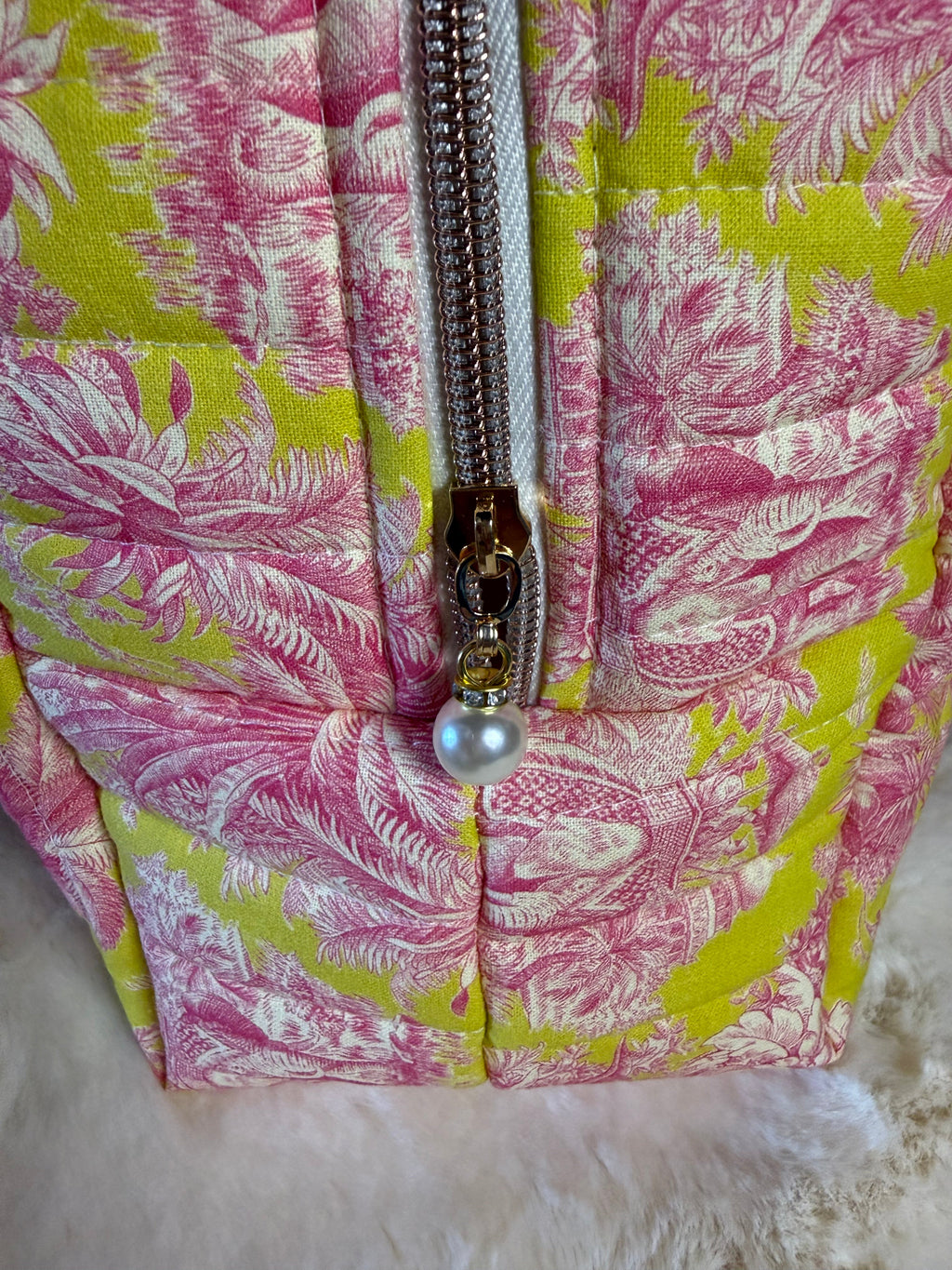 Détail de la fermeture éclair avec sa perle sur la toile de Jouy rose et jaune matelassée